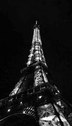 the eiffel tower lit up at night in black and white with its lights on