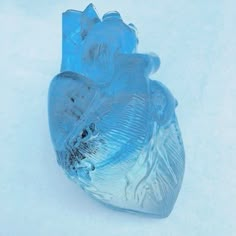 a glass heart sitting in the snow