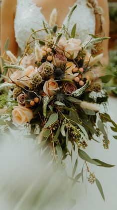 a bride holding a bouquet of flowers and greenery