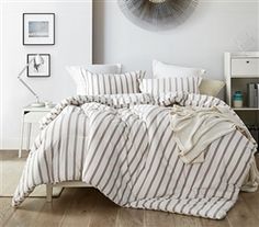 a bed with white and brown striped comforter in a room next to a wall