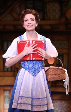 a woman in a blue and white dress holding a red box with her hands on it