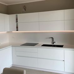 a modern kitchen with white cabinets and counter tops is lit by recessed lighting above the sink