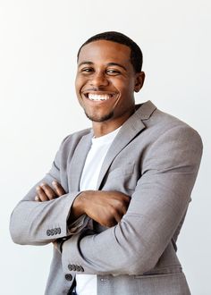 a smiling man in a gray suit with his arms crossed