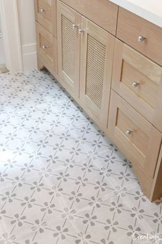 a bathroom with white and grey tile flooring next to a wooden sink vanity area