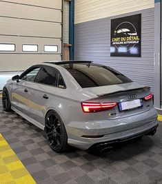 an audi car is parked in front of a garage door with yellow and black checkered flooring