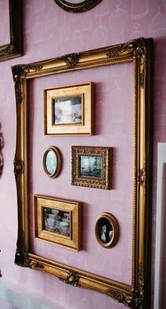 a pink wall with gold framed pictures on it