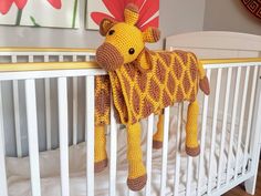 a crocheted giraffe stuffed animal hanging from the side of a crib