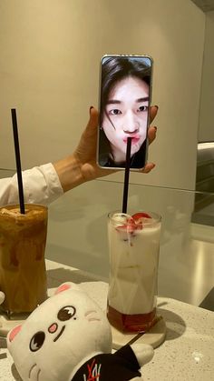 a person holding up a cell phone in front of a cup with an ice cream sundae on it