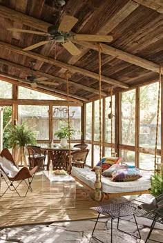 a porch with chairs, tables and a ceiling fan in the center is covered by wood planks