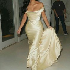 a woman in a long dress walking down a hallway