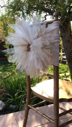 a chair with a flower on it sitting in front of a tree and some grass