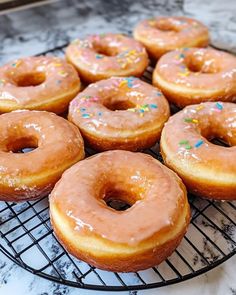 six glazed donuts sitting on a cooling rack