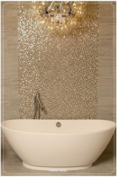 a white bath tub sitting under a chandelier next to a wall mounted light