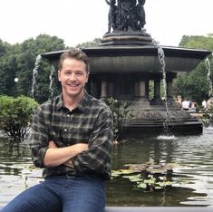 a man sitting on a bench in front of a fountain