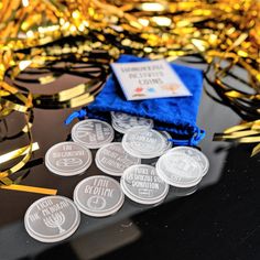 some silver and gold confetti sitting on top of a table next to a blue bag