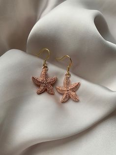 Grab these starfish earrings that are the perfect for a beach day or any occasion! These rose gold star fish earrings have an elegant feel. - Handmade by me  - Hypoallergenic gold plated 304 stainless steel hooks - All earrings come with a rubber back. - Your purchase will come in a card holder, bag, and a bag of sweets 🍬  - For hygiene reasons NO RETURNS OR     REFUNDS. - FREE SHIPPING Care info:  Please take care of your handmade earrings. Do not sleep in them, come into contact with water wi Gold Star Earrings For Summer, Elegant Star-shaped Summer Earrings, Rose Gold Star Charm Earrings, Rose Gold Star Earrings With Star Charm, Rose Gold Star-shaped Earrings With Star Charm, Ocean-inspired Starfish Charm Earrings, Elegant Star-shaped Earrings For Summer, Elegant Summer Star-shaped Earrings, Rose Gold Star Earrings For Gift