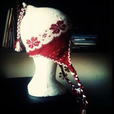 a white mannequin head wearing a red and white knitted hat