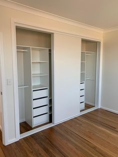 an empty room with white closets and wooden floors