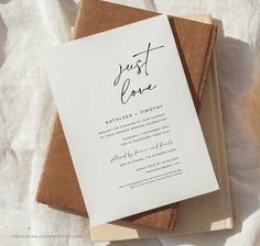 a wedding program is laying on top of a brown and white book with the word just love written in cursive ink