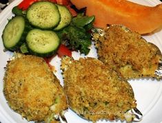 a white plate topped with three pieces of fried fish next to vegetables and a slice of melon