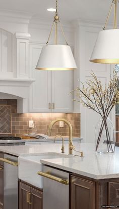 a kitchen with two lights hanging over the sink and an island in front of it