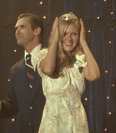 a man and woman standing next to each other in front of a blue curtain with lights