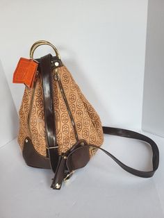 This beautiful backpack sling bag from Marino Orlandi is a perfect blend of elegance and functionality. With a brown leather exterior, printed croc embossing, and gold-plated hardware, this bag is sure to turn heads. The cylinder shape and adjustable strap make it suitable for a variety of occasions, from travel to formal events. The bag features multiple inner and outer pockets, bottom studs for stability, and a lined interior. The logo embossed pattern and theme options, like motorcycle and bohemian, make it a statement piece. Made in Italy with high-quality leather, this bag is a must-have for any fashion-forward individual. Elegant Brown Backpack With Leather Backing, Elegant Brown Backpack With Adjustable Strap, Brown Leather Backpack For Formal Occasions, Formal Brown Leather Standard Backpack, Formal Brown Leather Backpack, Luxury Brown Leather Backpack For Everyday, Elegant Brown Backpack-style Shoulder Bag, Elegant Brown Backpack Shoulder Bag, Luxury Backpack With Detachable Handle