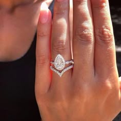 a close up of a person's hand with a diamond ring on her finger