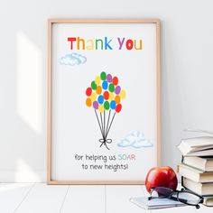 an apple and some books are sitting on the floor next to a framed poster that says thank you for helping us soar to new heights