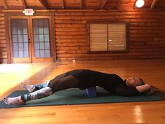 a woman is doing yoga on a mat in the middle of a room with wooden walls