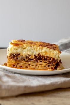 a white plate topped with lasagna covered in cheese