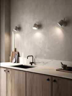 a kitchen with two lights on the wall and a sink in the middle, next to a counter