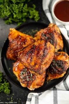 grilled chicken wings on a black plate next to a cup of tea and parsley