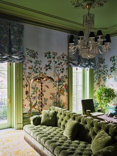 a living room with green couches and chandelier