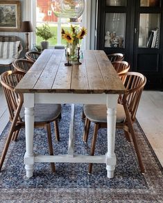 a dining room table with chairs and a vase filled with sunflowers on it