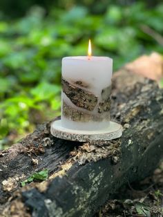 a lit candle sitting on top of a piece of wood