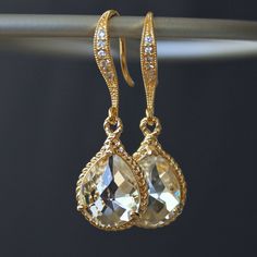 These beauties are standouts! Perfect for that special occasion! Elegant jeweled, french earrings carry stunning, teardrop crystals with a gold rope trim. The crystal detail on these earrings gives them such a classy and sophisticated feel. The last two pictures are for size reference. Details: * Gold-plated French Earrings * Faceted Crystal- 19 x 12mm(3/4x1/2") including rope trim * Length- 32mm(1 1/4") * Tarnish Resistant * Nickel and Lead-free These earrings come in an organza bag and gift box. Gold Teardrop Earrings With Diamond Accents For Wedding, Glamorous Gold Sparkling Teardrop Earrings, Glamorous Gold Teardrop Earrings For Evening, Glamorous Gold Teardrop Earrings, Gold Sparkling Drop Jewelry, Evening Gold Pear-shaped Jewelry, Gold Pear-shaped Jewelry For Evening, Gold Teardrop Bridal Earrings For Formal Occasions, Gold Pear-shaped Teardrop Earrings For Evening