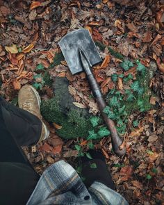 a person standing in leaves with an axue and shovel on top of them,