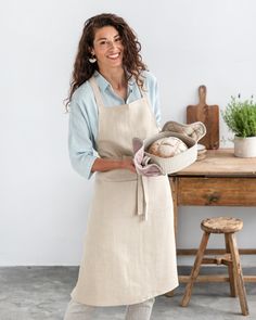 a woman in an apron holding some bread