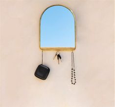 a mirror hanging from the side of a wall with keys and a chain attached to it