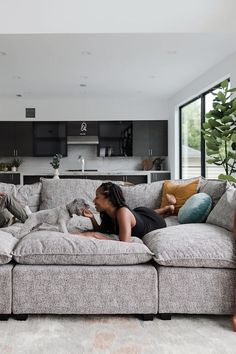 a woman laying on top of a couch next to a dog