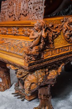 an elaborately carved wooden bench with carvings on it's sides and feet,