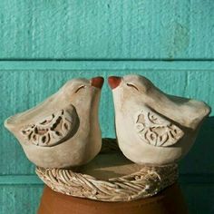 two ceramic birds sitting on top of a pot