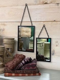 three mirrors hanging on the wall above a shelf filled with pillows and other decorative items