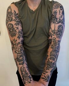 a man with many tattoos on his arm and arms, standing in front of a white wall