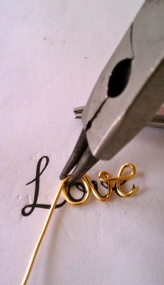 a pair of scissors cutting the word love out of paper with gold colored metal wire