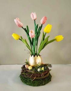 an arrangement of pink and yellow tulips in a nest