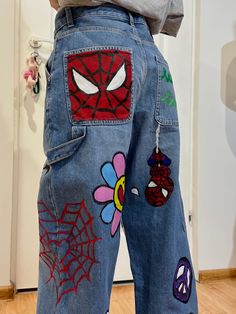 a person with spiderman patches on their jeans, standing in front of a door