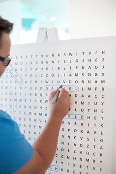 a woman is writing on a large white piece of paper that has words in it