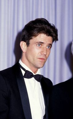 a man in a tuxedo standing next to an older man wearing a suit